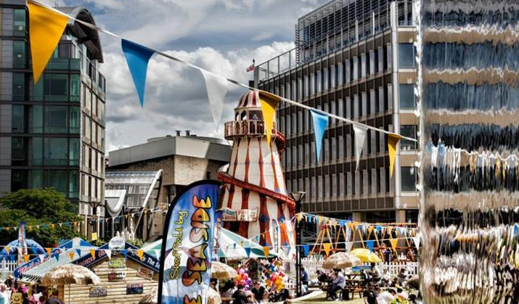 A photo showing the Peace Gardens in Sheffield, decorated with blue and white bunting and with a helter skelter in the centre.