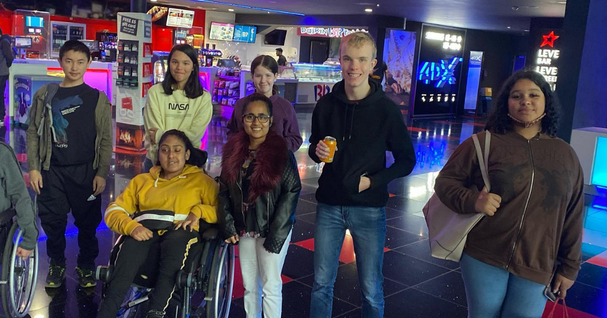 Seven teenagers pose for a photo in a cinema.