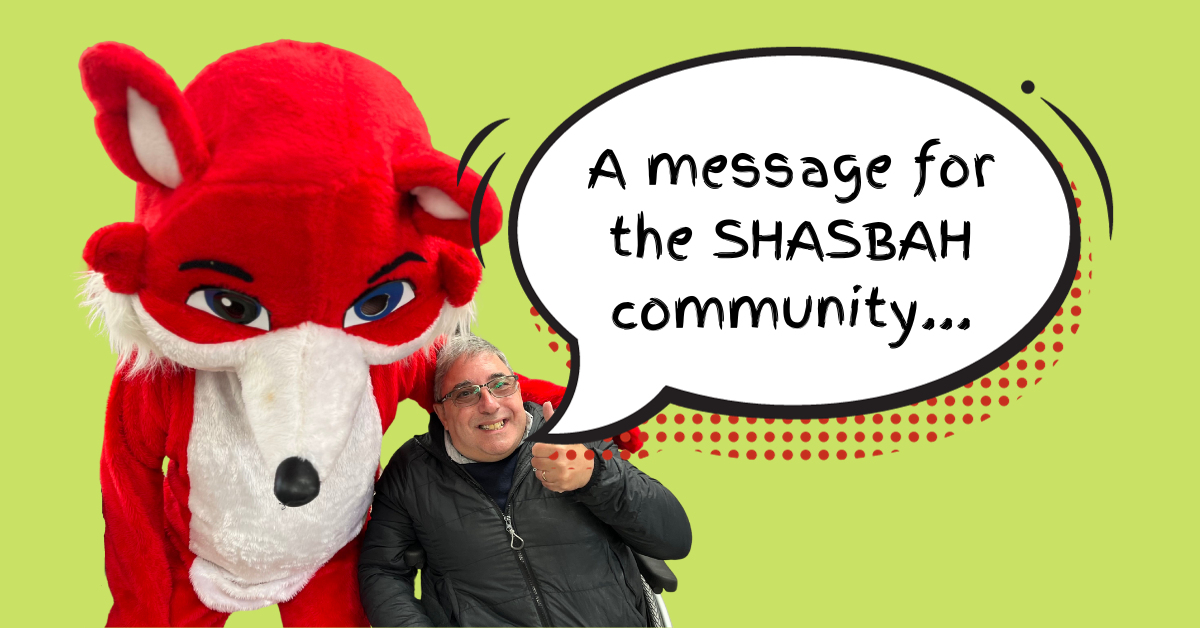 A Man Poses For A Photo With Shasby, The Red Fox Mascot Of SHASBAH. A Cartoon Speech Bubble Says, 'A Message For The SHASBAH Community'.